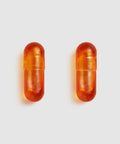 Two Juice Plus+ Omega orange capsules on a light gray background