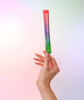 Hand holding a Juice Plus+ Superfood Powder packet against a gradient background