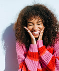 Woman wearing a pink and red striped sweater against a light blue background