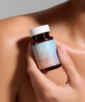 Hand holding a bottle of Juice Plus+ Super Biome Probiotic against a neutral background
